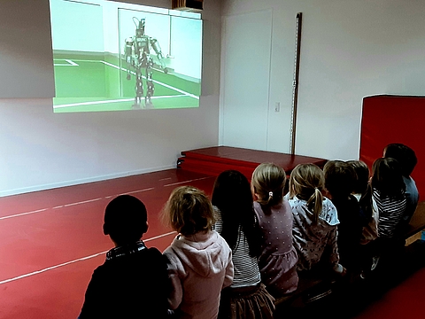 Die Kinder schauen einen Film über einen Roboter, der Fußball spielen kann
